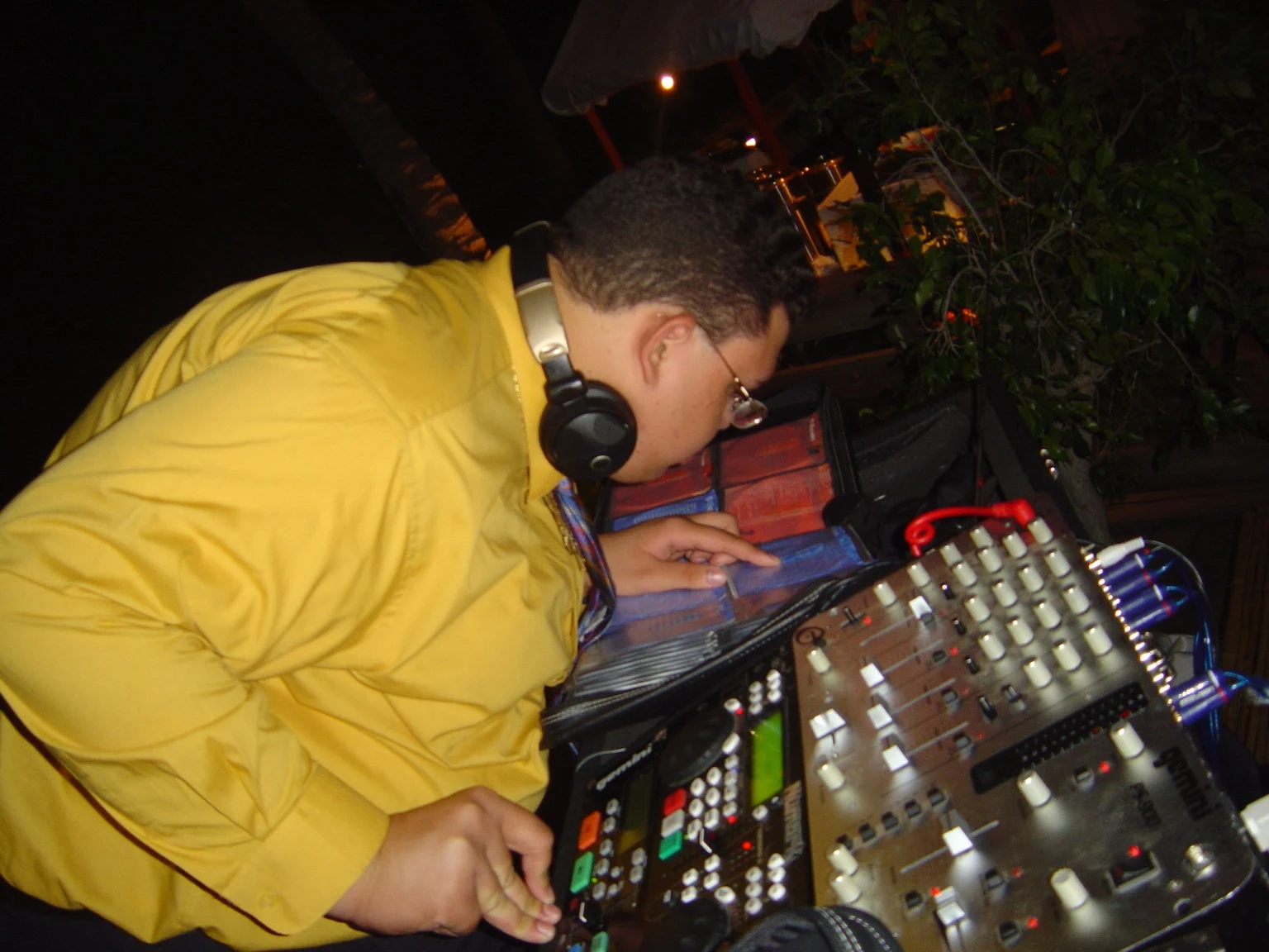 Archive close-up of Ruuben selecting music beside a mixer and CD collection