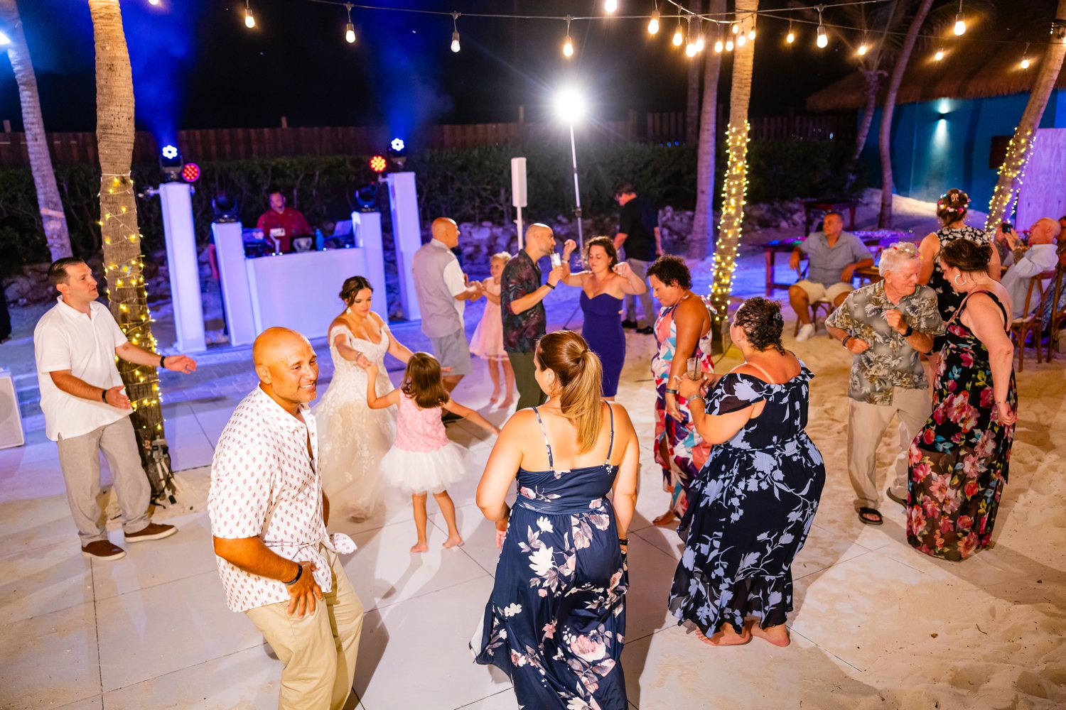 Wedding guests dancing together beneath palm trees