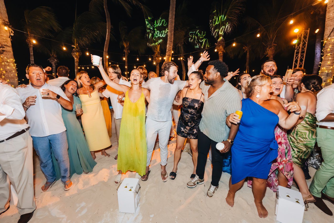 A bride, groom and their wedding guests celebrating together under string lights