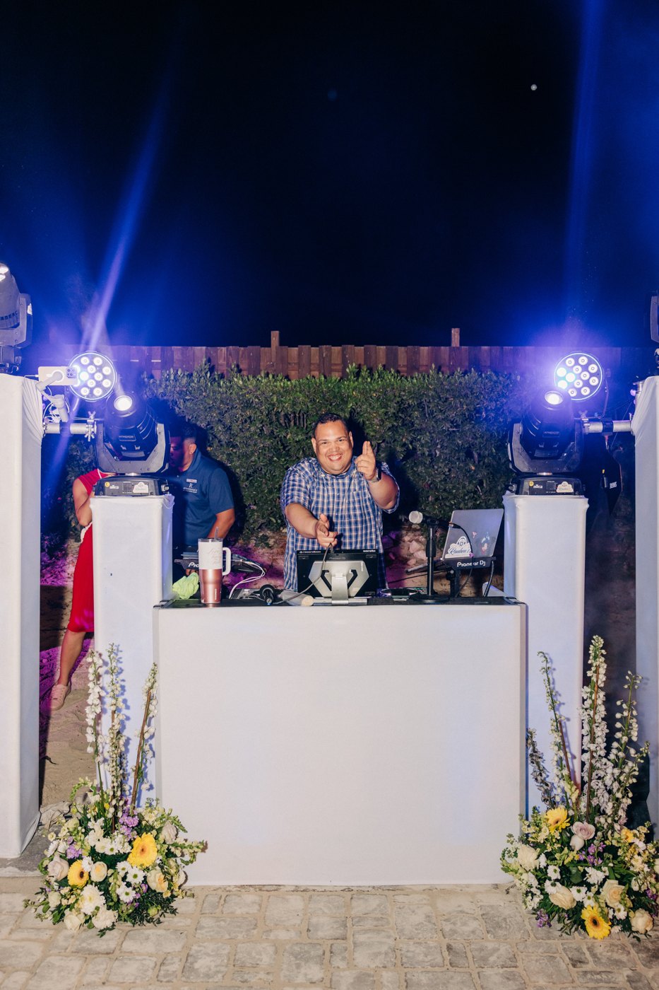 White DJ booth with floral arrangements and evening lighting